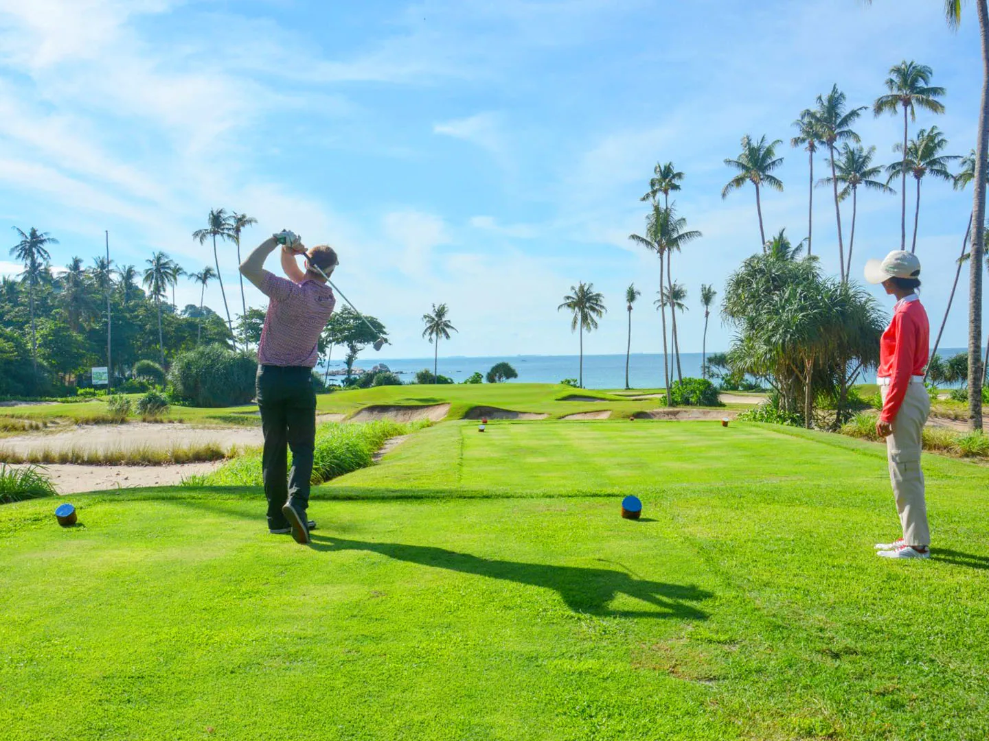 A golfer finishing a swing on a seaside course at Bintan Resorts
