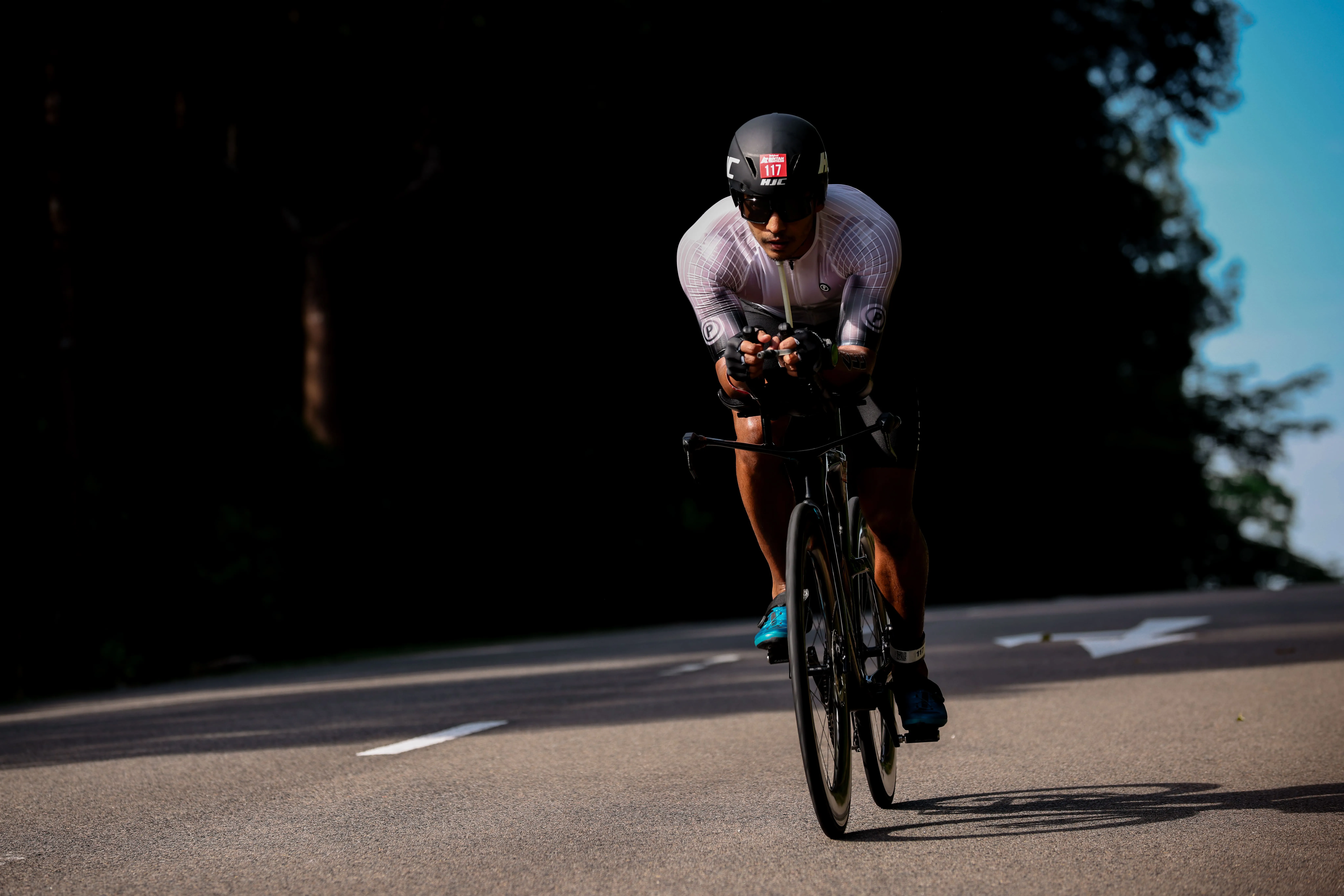 A triathlete riding a time-trial bike along Bintan's palm-lined coastal road